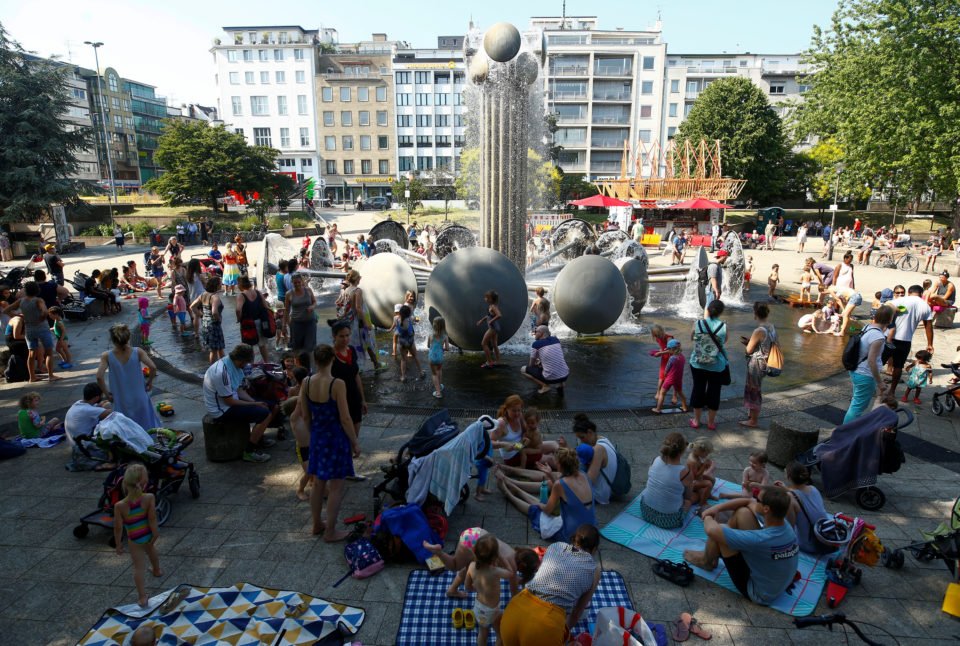 People relax next to a fountain on a square on a hot summer day in Cologne, Germany, June 26, 2019. REUTERS/Thilo Schmuelgen