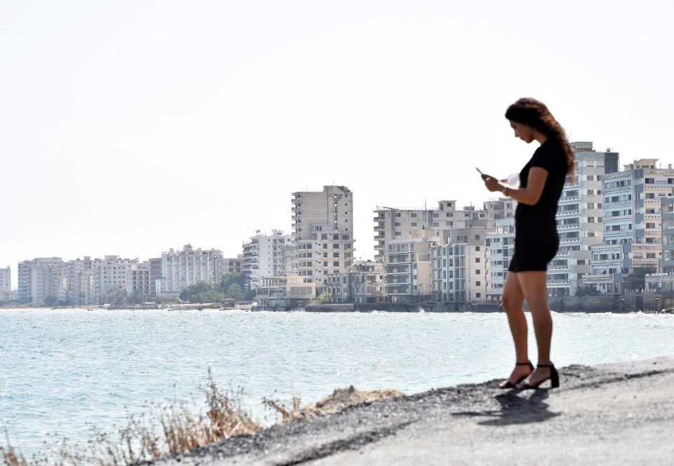 A Woman Looks At Her Mobile Phone In The Abandoned Coastal Area Of Varosha