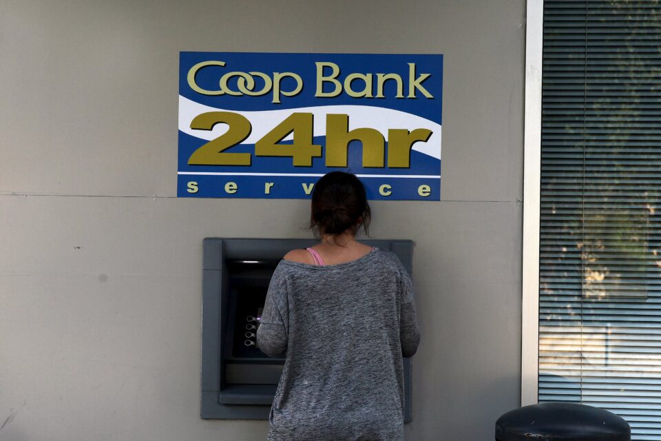 A Woman Makes Transaction At An Atm Outside A Branch Of Co Op Bank In Nicosia,