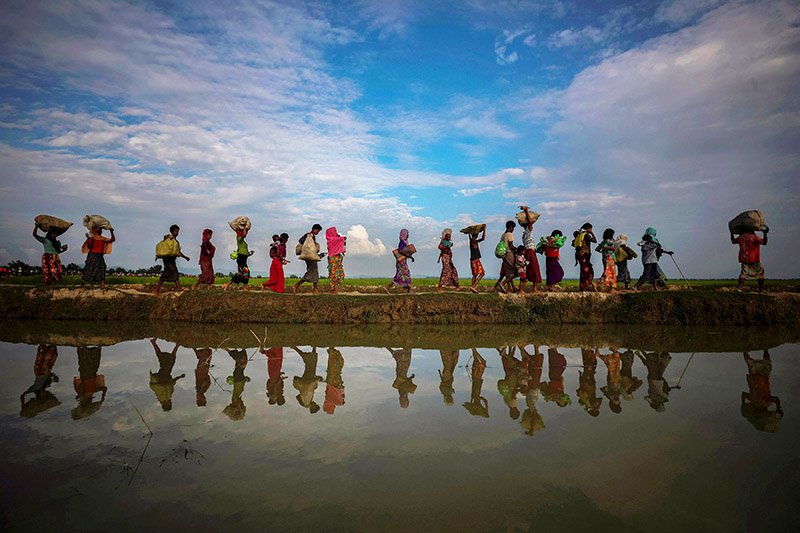 file photo: rohingya refugees are reflected in rain water along an embankment next to paddy fields after fleeing from myanmar into palang khali