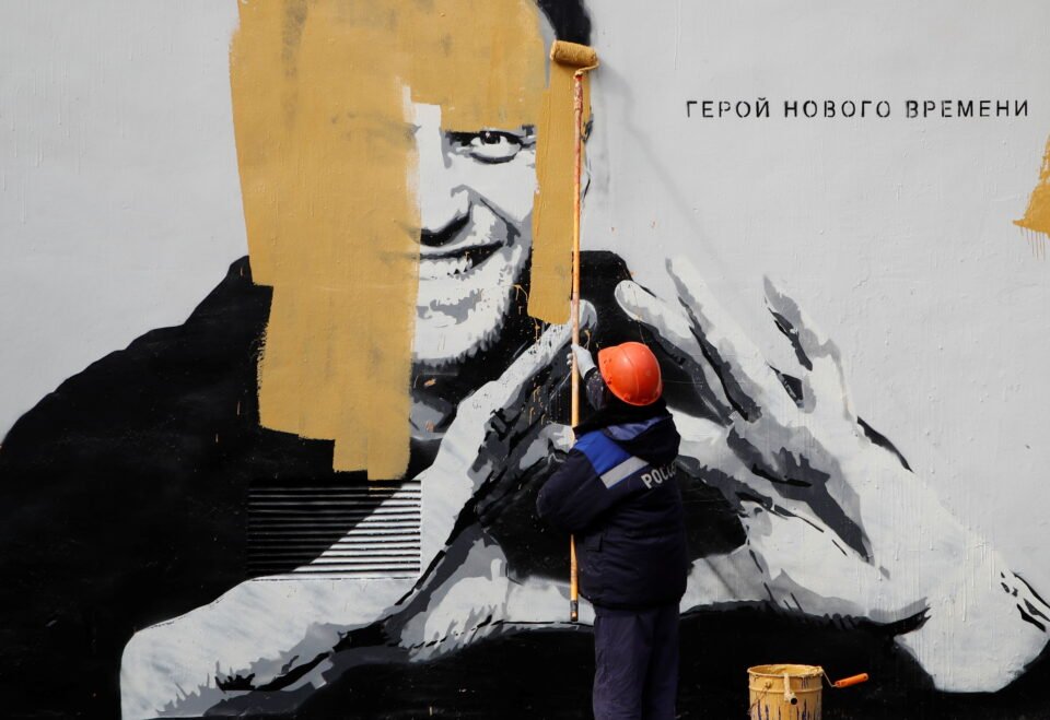 a worker paints over a graffiti depicting alexei navalny in saint petersburg