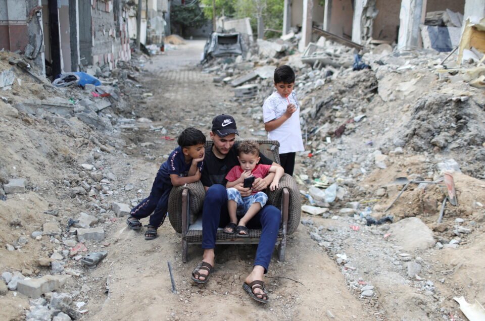 palestinians sit amid the rubble of their houses which were destroyed by israeli air strikes