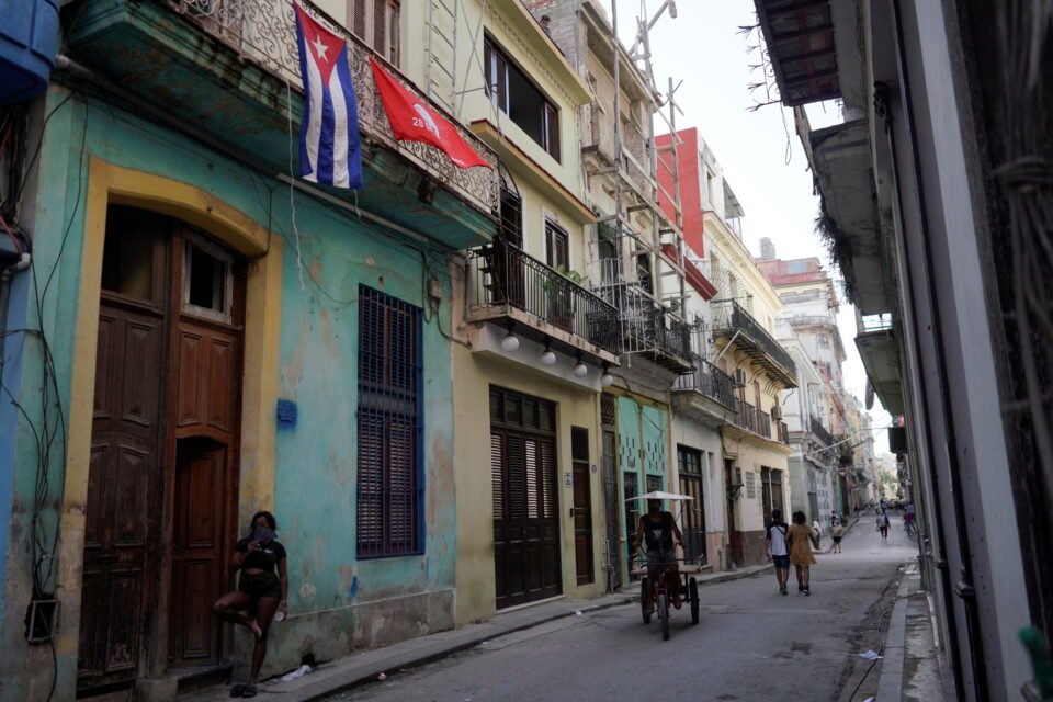 a cuban flag hangs on the balcony of a house in havana