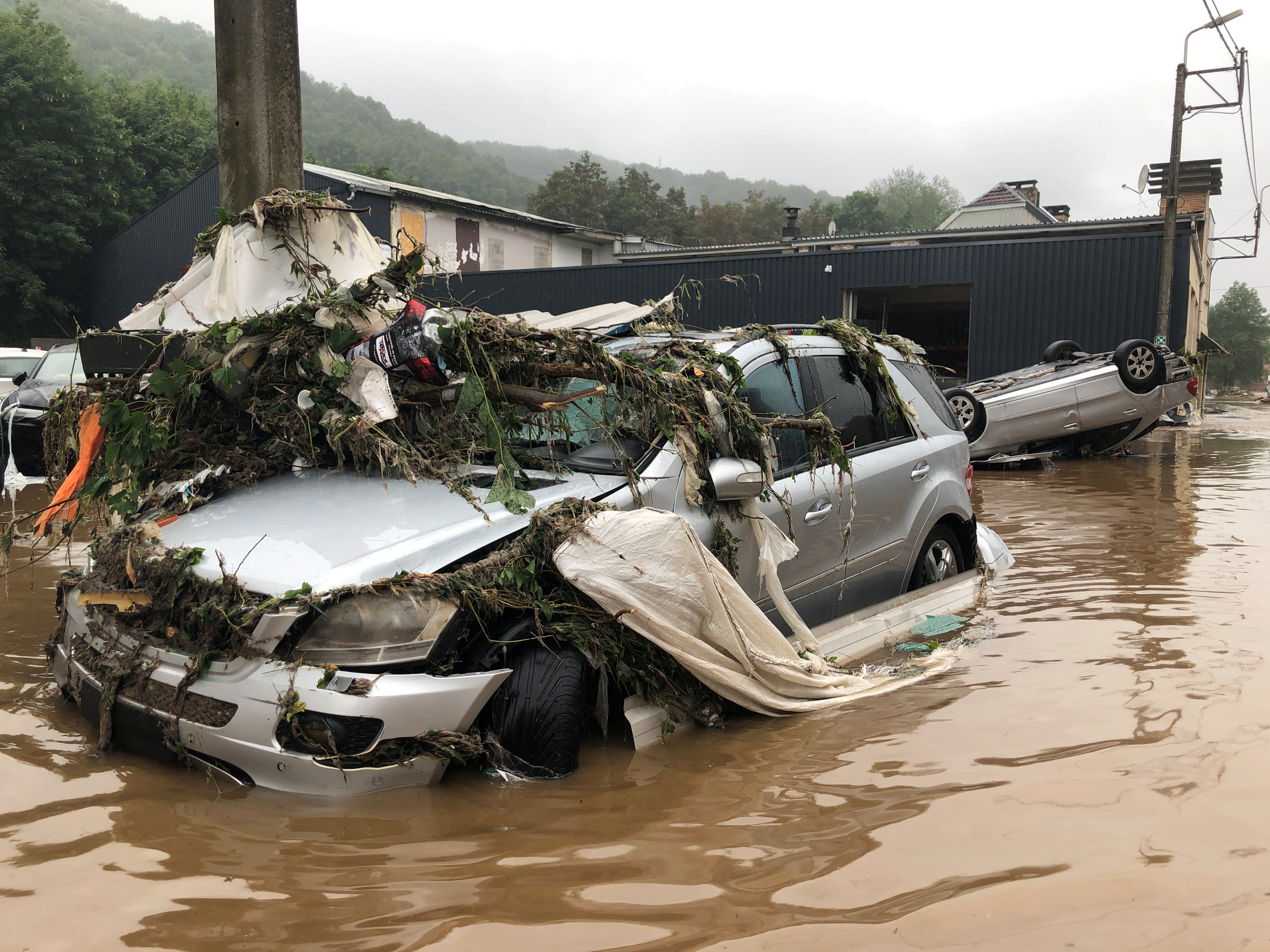 damaged cars and debris are seen on a flooded street in pepinster