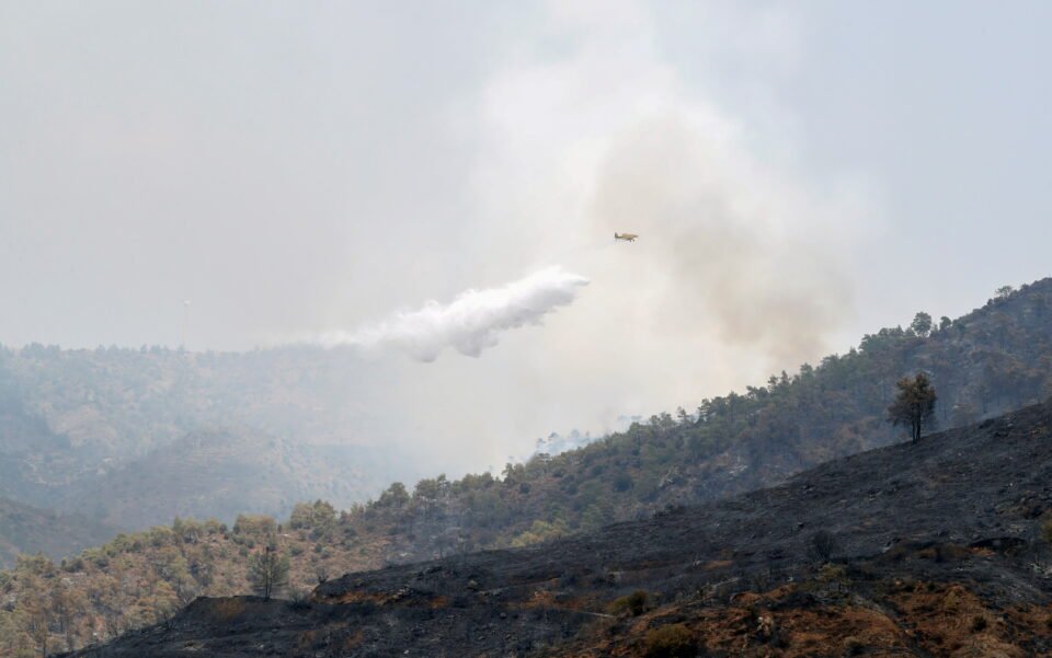 a firefighting plane drops water on a wildfire in the larnaca mountain region