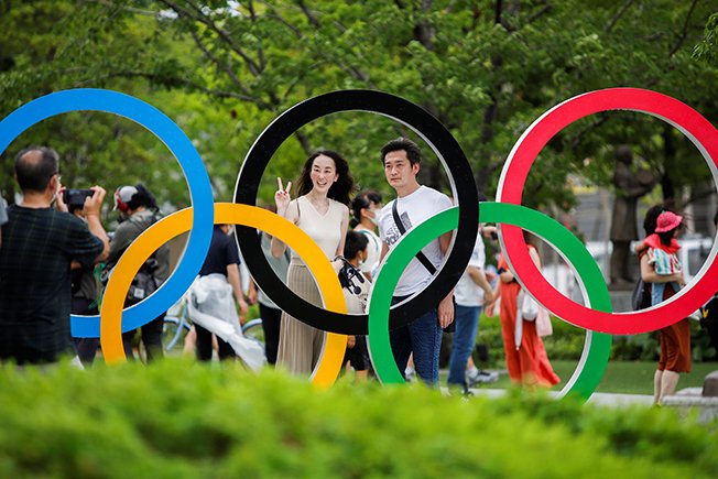 people pose for photos at the olympic rings in front of the olympic stadium, one day after the end of the tokyo 2020 olympic games in tokyo