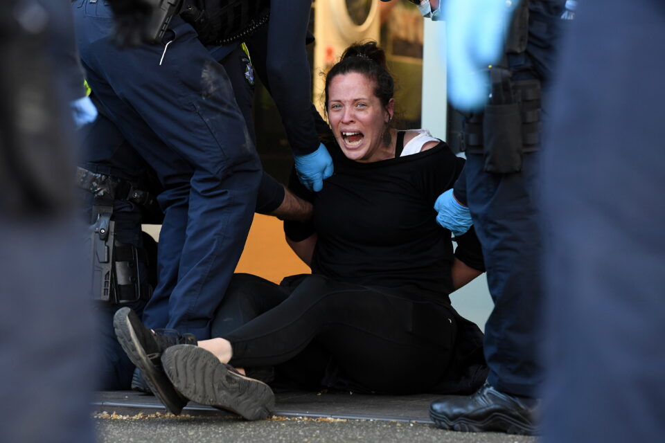 a protester is detained by victoria police during a "the worldwide rally for freedom" demonstration in melbourne