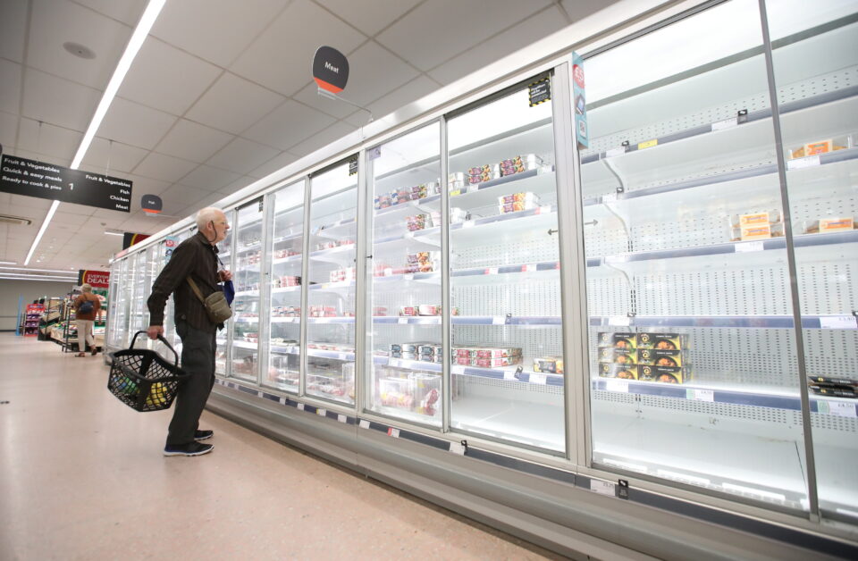 a shopper looks at produce and empty shelves of the meat aisle in co op supermarket, harpenden