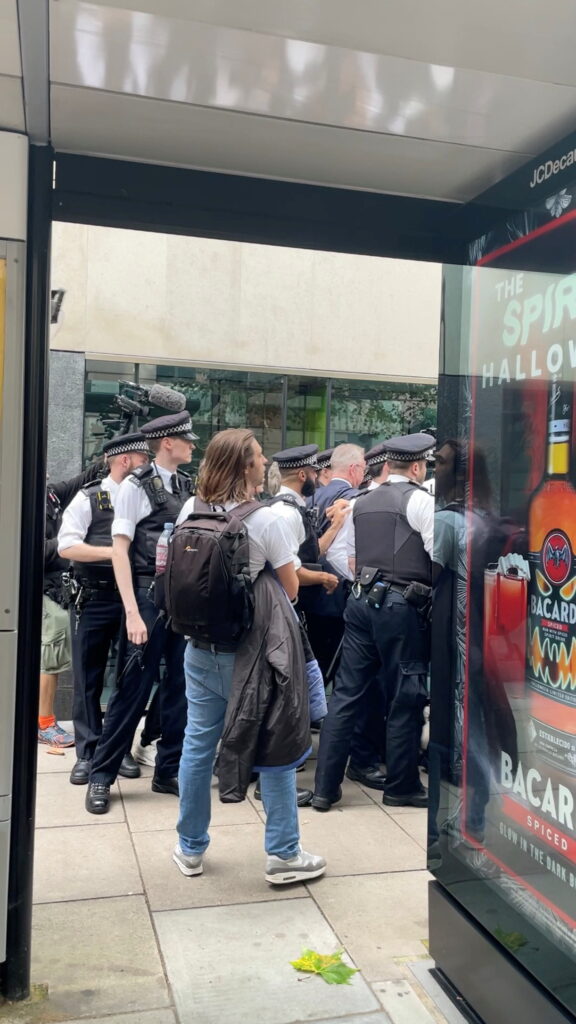 britain's housing secretary michael gove walks while surrounded by police officers and protesters, in london
