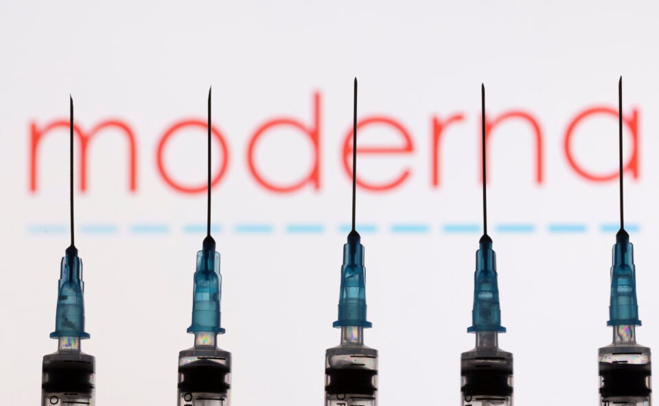 syringes with needles are seen in front of a displayed moderna logo in this illustration taken