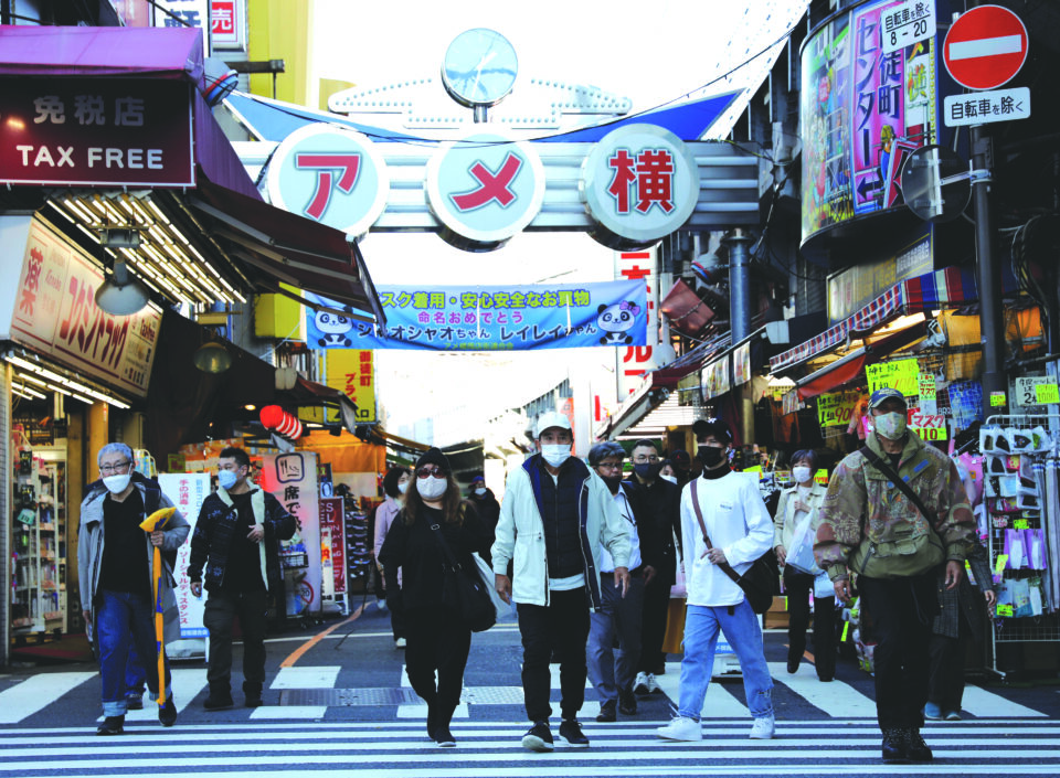 pedestrians wearing protective masks, amid the coronavirus disease (covid 19) outbreak, make their way at the ameyoko shopping district in tokyo