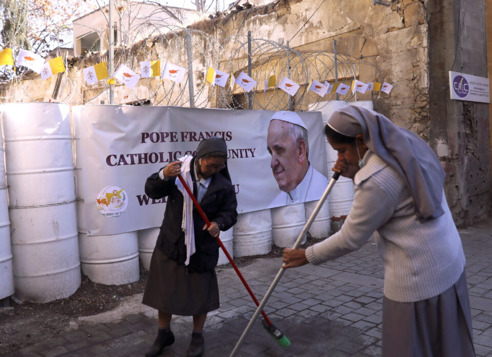 Nuns clean the road in front of the Holy Cross Catholic Church 