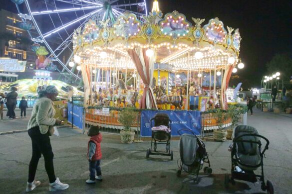 A small child looks expectantly at his mother in front of the carousel