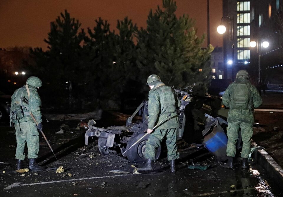 specialists inspect a wreckage of a car that according to the local authorities was blown up in donetsk