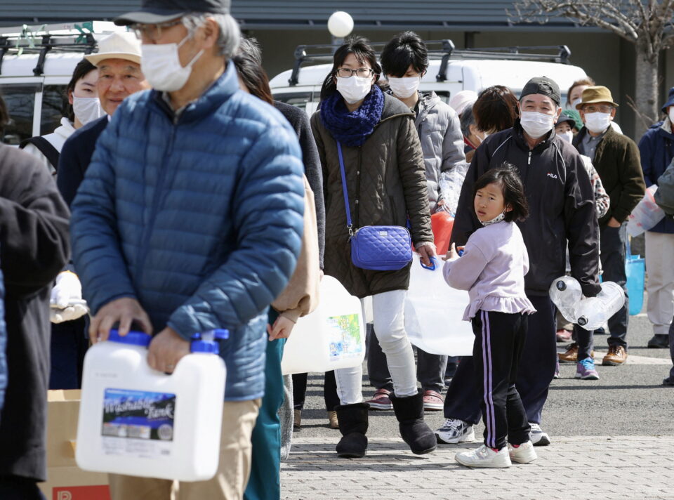 people wait in line to receive water following a strong earthquake in kunimi