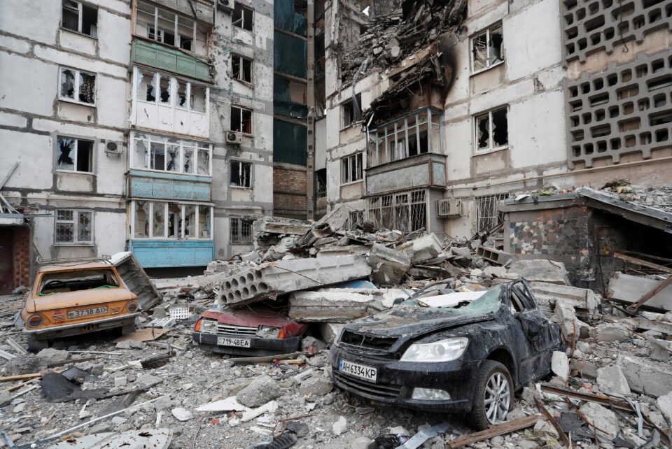 destroyed cars are seen in front of a heavily damaged apartment building in the besieged city of mariupol
