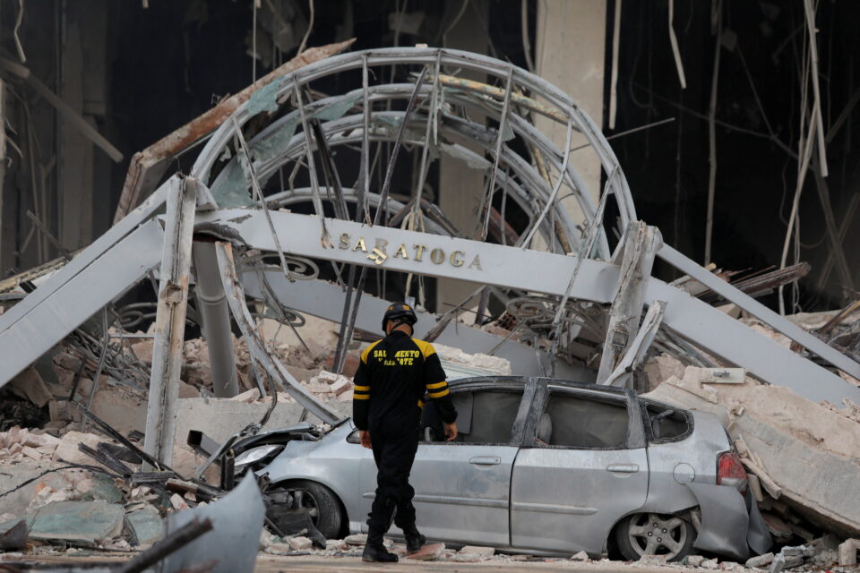A member of the emergency services inspects the area as a destroyed car is seen after an explosion hit the Hotel Saratoga, in Havana, Cuba May 6, 2022. REUTERS/Alexandre Meneghini