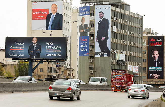 cars pass near electoral campaign billboards of candidates running for lebanon's parliamentary election, in dora