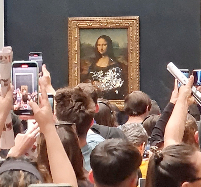 image Mona Lisa unharmed but smeared in cream in climate protest stunt