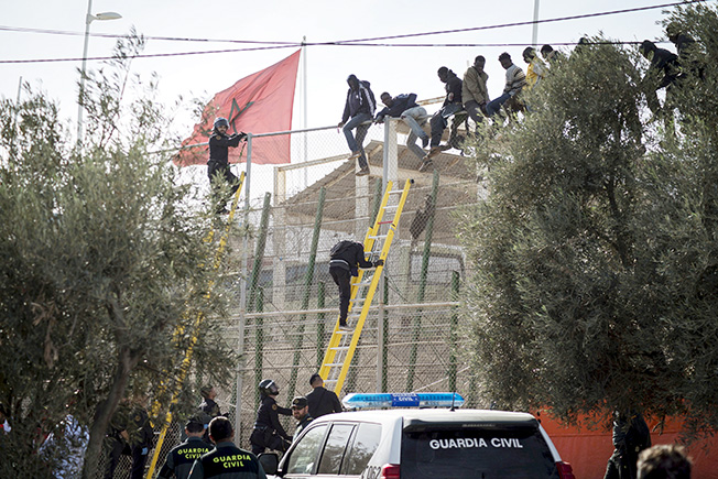 file photo: african migrants sit on top of a border fence during an attempt to cross into spanish territories, between morocco and spain's north african enclave of melilla