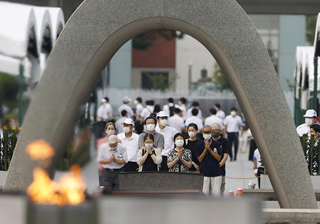 people pray in front of the cenotaph for the victims of the 1945 atomic bombing at peace memorial park in hiroshima, japan