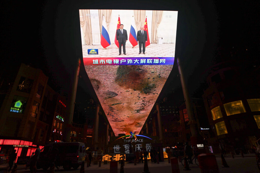 a giant screen broadcasts news footage of chinese president xi jinping and russian president vladimir putin posing for pictures on the sidelines of the sco summit in uzbekistan, in beijing