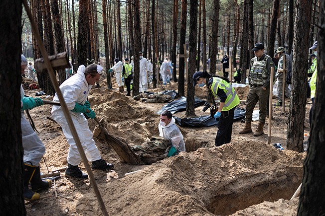 experts work at a forest grave site during an exhumation in izium