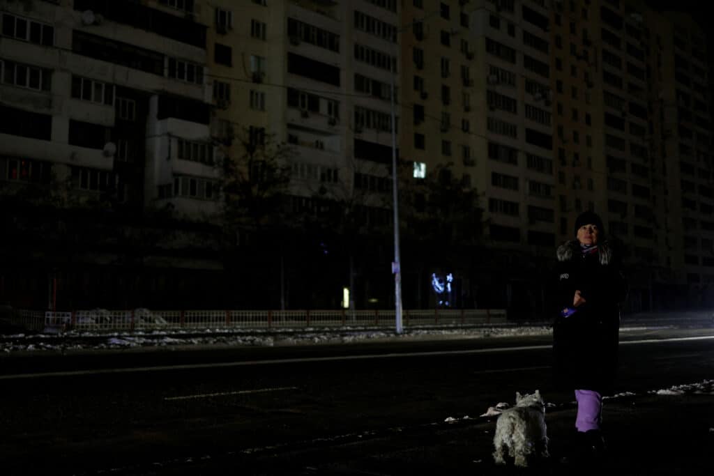 file photo: woman with a dog waits for a bus in a street without electricity after critical civil infrastructure was hit by russian missile attacks in kyiv