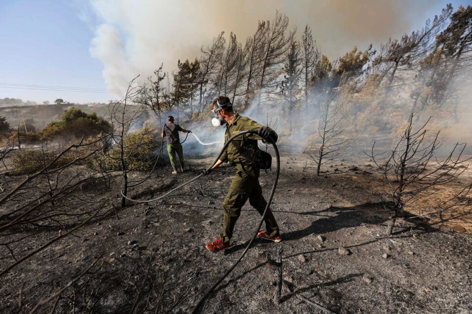 Volunteers try to extinguish a wildfire burning in the village of Vati, 