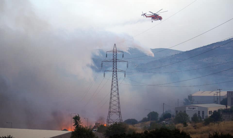 A firefighting helicopter makes a water drop next to an electricity tower as a wildfire burns at the industrial zone of the city of Volos REUTERS/Stamos Prousalis