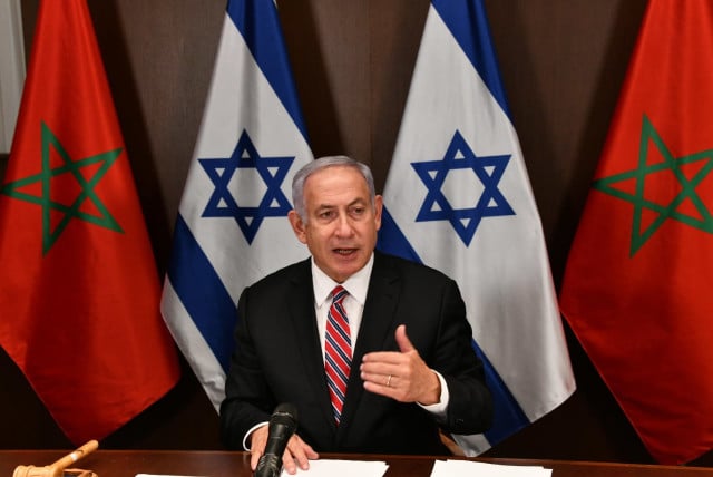 benjamin netanyahu stands in front of the flags of israel and morocco