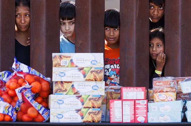 cover Migrants &#8216;from all over the globe&#8217; gather between California border barriers