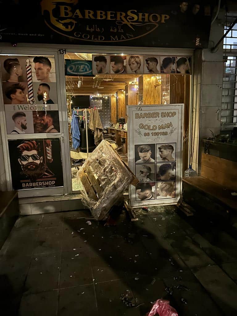 a syrian owned barbershop with a smashed front window