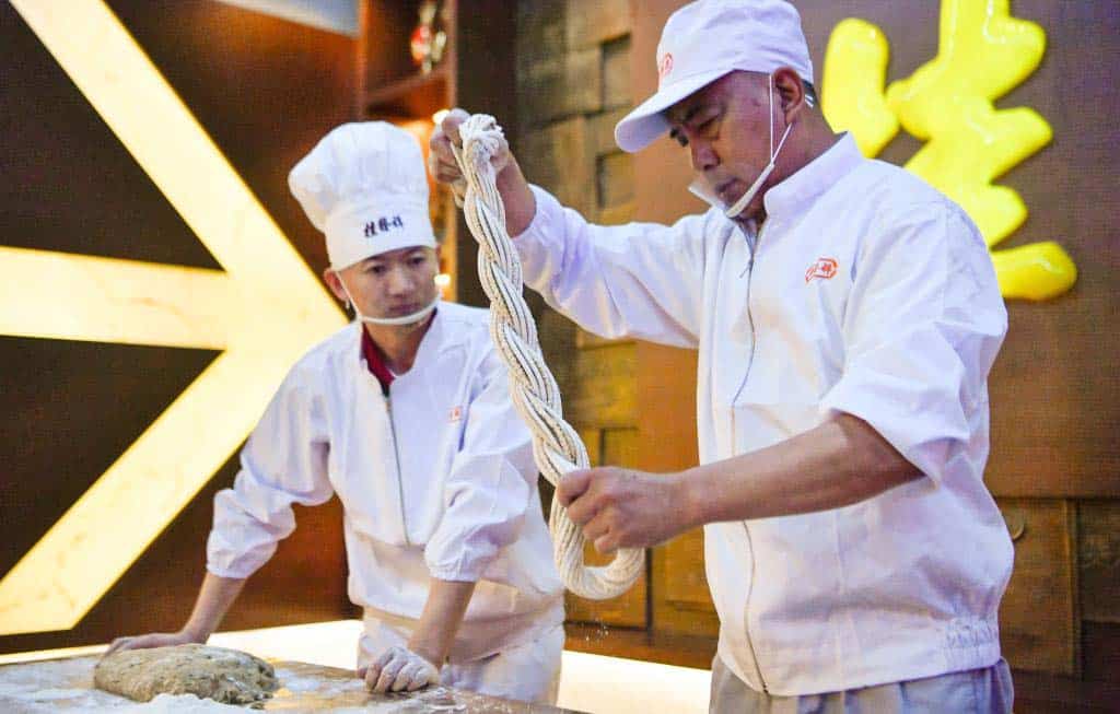 feature2 wang hongde instructs his apprentice zhao baoyang in making fried dough twists in north china's tianjin