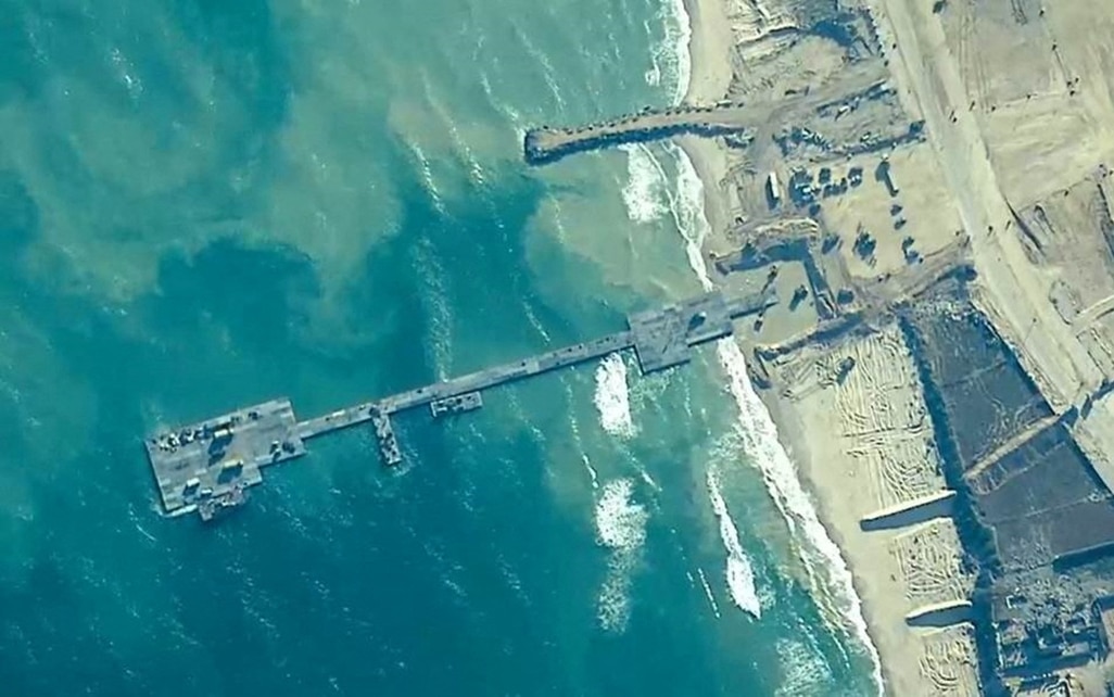 cover Aid trucks begin moving ashore via Gaza pier, US says