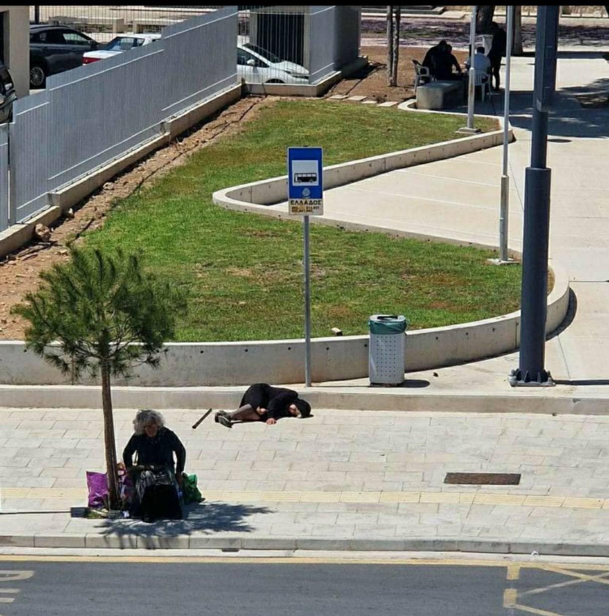 image Fury over old woman lying on pavement at Paphos bus stop