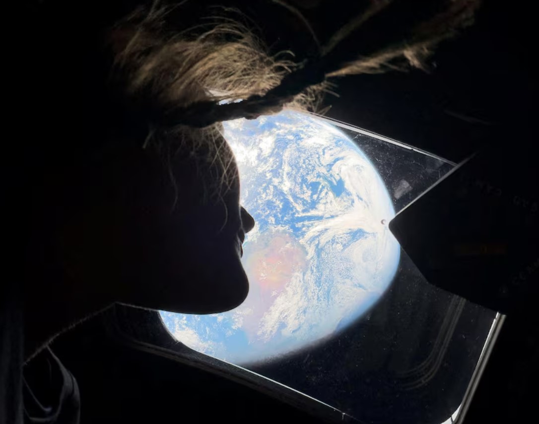 NASA astronaut and Artemis II mission specialist Christina Koch peers out of one of the Orion spacecraft's main cabin windows, looking back at Earth, as the crew travels towards the Moon, April 2. NASA/Handout via REUTERS