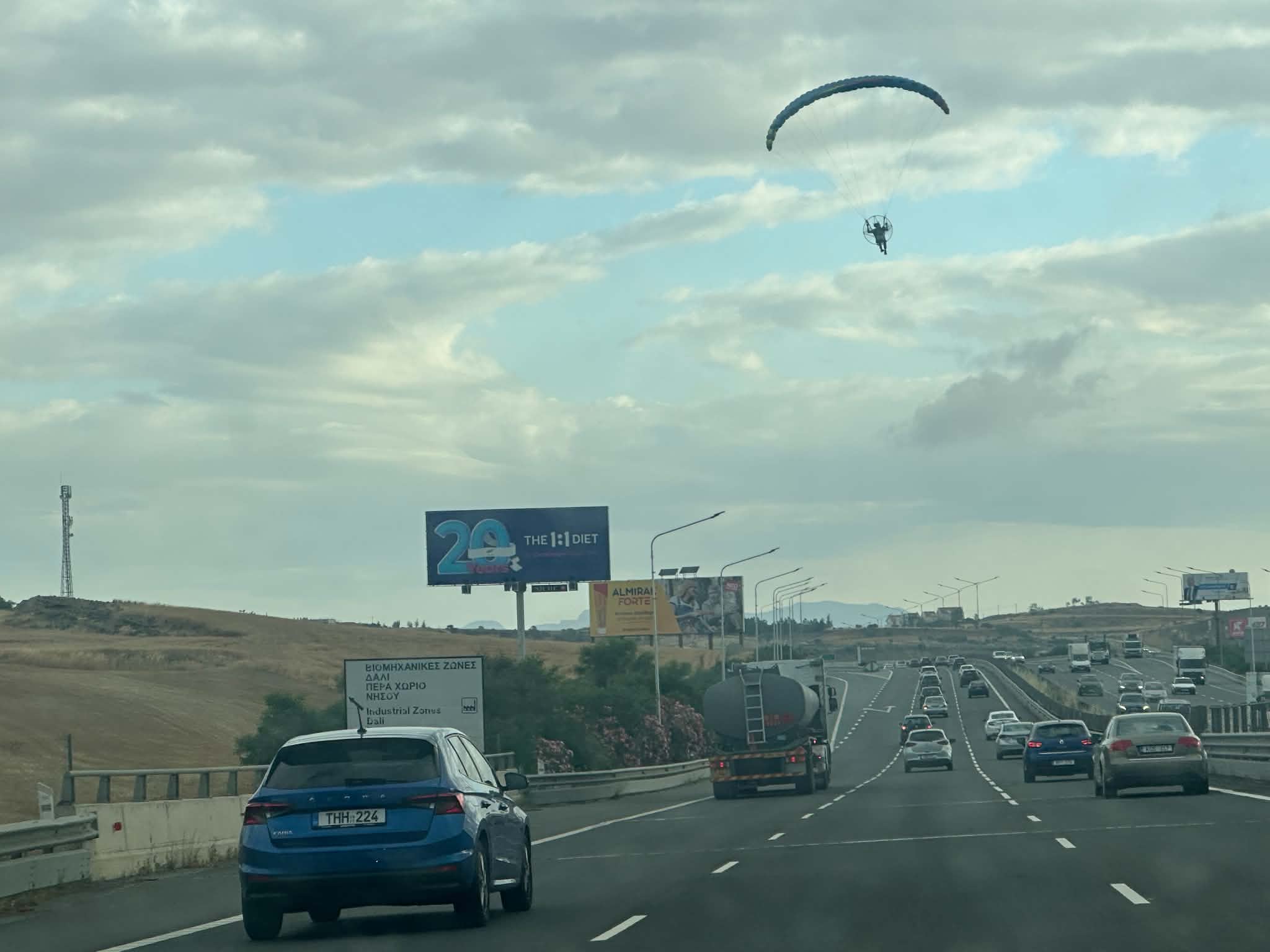 cover Paraglider drifts over busy motorway